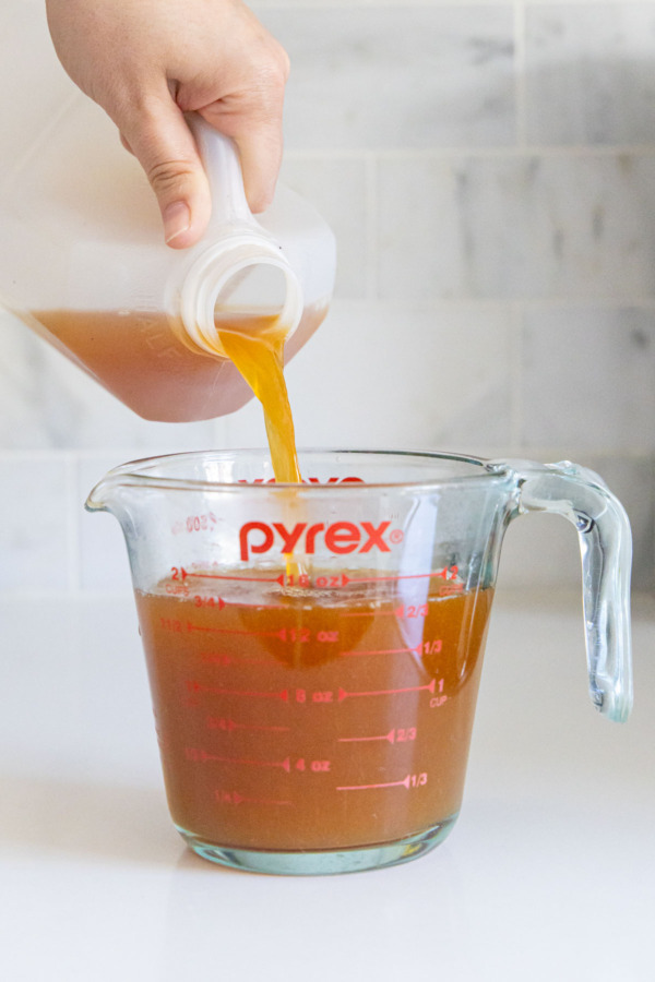 Pouring fresh apple cider into measuring cup to make 2 cups.